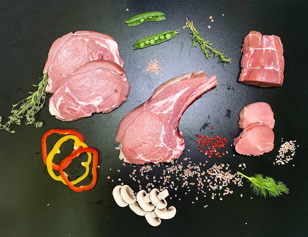 Assortiment de viandes crues : côtelettes, rôti, tournedos, avec légumes et aromates sur noir Le Passage près d'Agen dans le Lot-et-Garonne 47