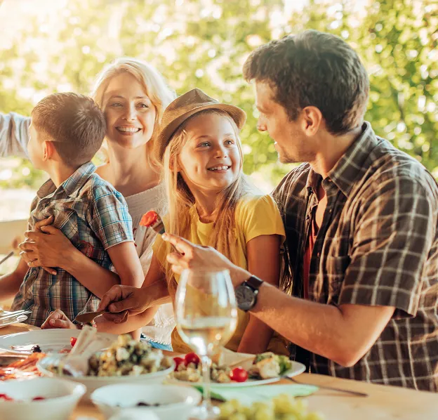 Famille heureuse et enfants souriants déjeunant à l'extérieur.