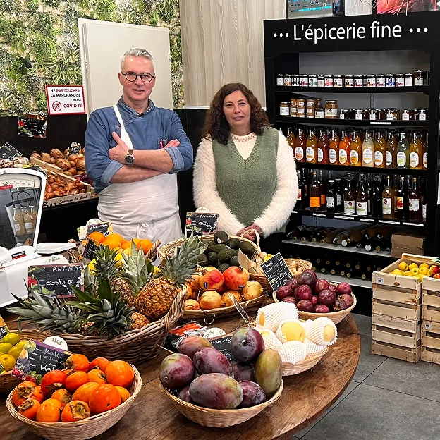Marché français avec deux propriétaires souriants et un étal de fruits frais Le Passage près d'Agen dans le Lot-et-Garonne 47